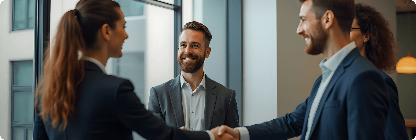 Two business professionals shaking hands in front of a large window, symbolizing a successful partnership or agreement.